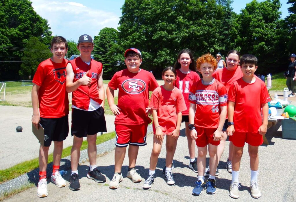 Young girls and boys in red shirts standing in a row and smiling