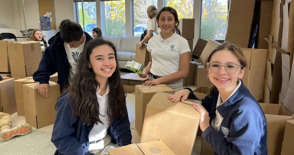 Smiling female students in school uniforms assembling boxes