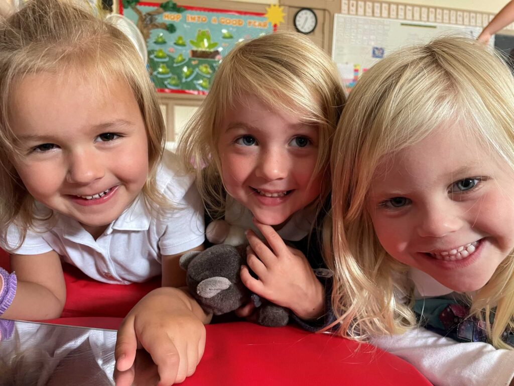 Three young girls in school uniforms smiling.