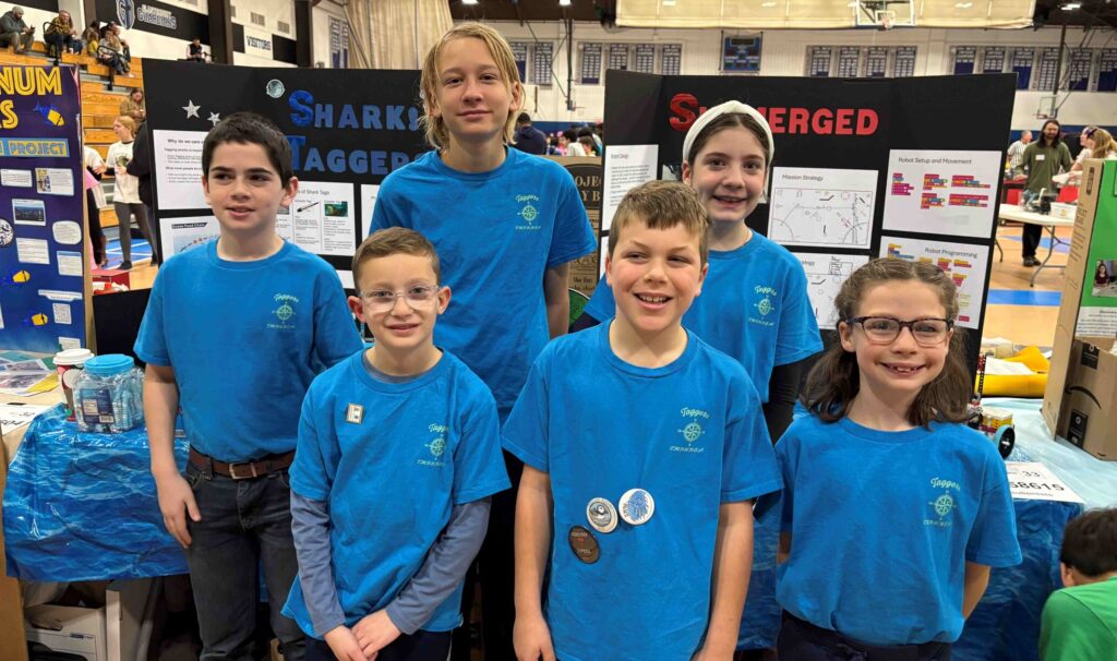 Group of students in blue tshirts in front of display